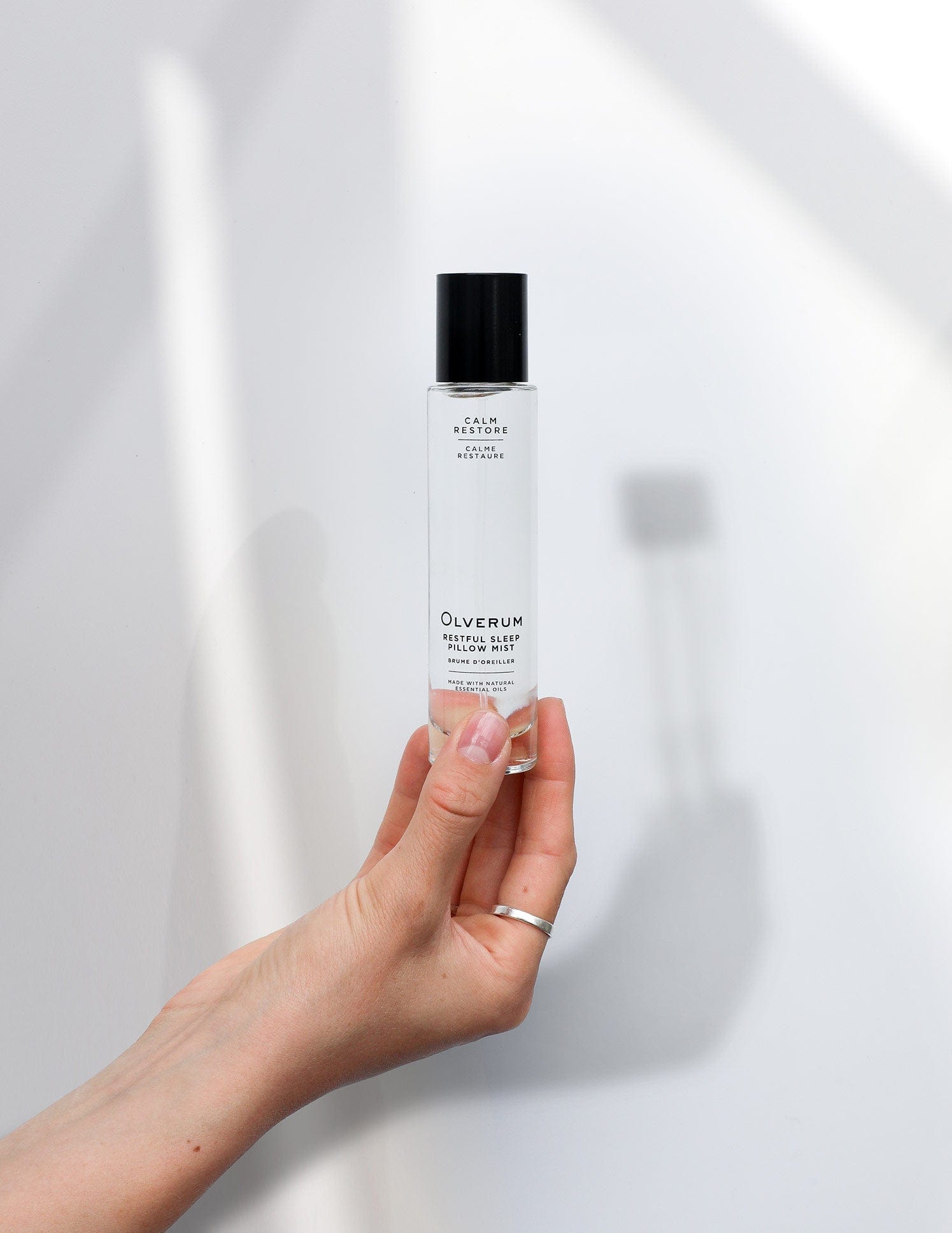 Hand holding Olverum Restful Sleep Pillow Mist 50ml, a sleek aromatherapy spray for calming nighttime wellness rituals.