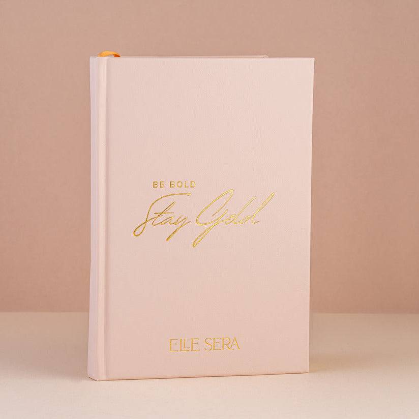 Three-Month Wellness Journal - Growth &amp; Habits | Daily Clarity in blush pink hardcover with gold embossed text &#39;Be Bold Stay Gold&#39; by Elle Sera. Ideal for tracking wellness, habits, and mindfulness.