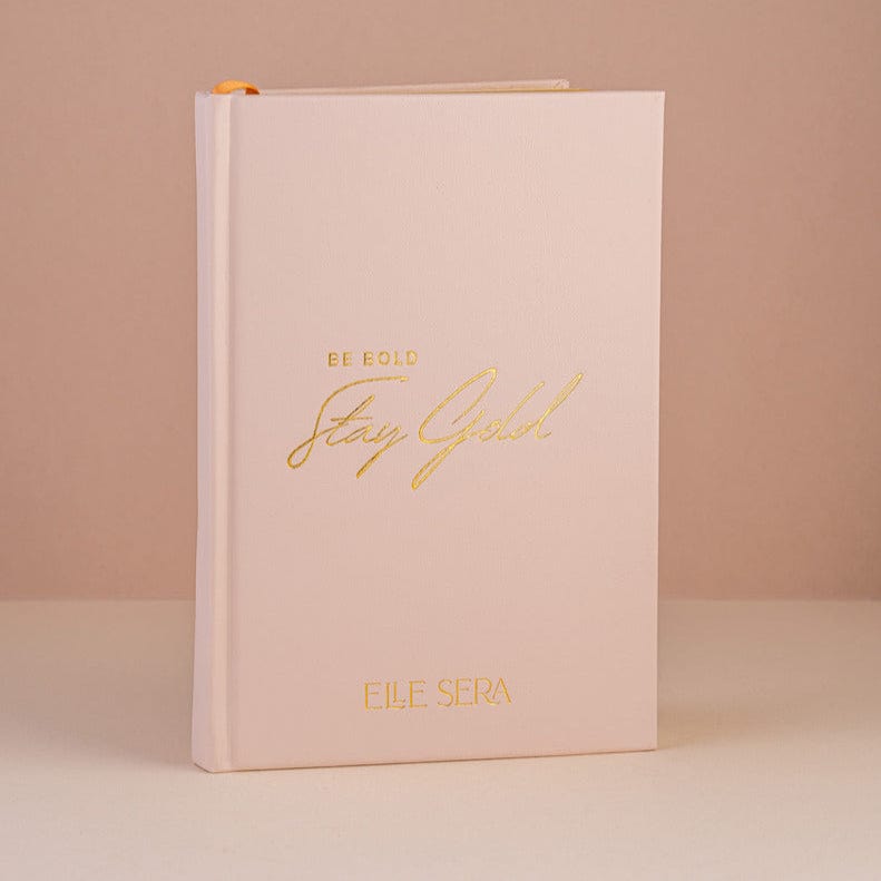 Three-Month Wellness Journal - Growth & Habits | Daily Clarity in blush pink hardcover with gold embossed text 'Be Bold Stay Gold' by Elle Sera. Ideal for tracking wellness, habits, and mindfulness.
