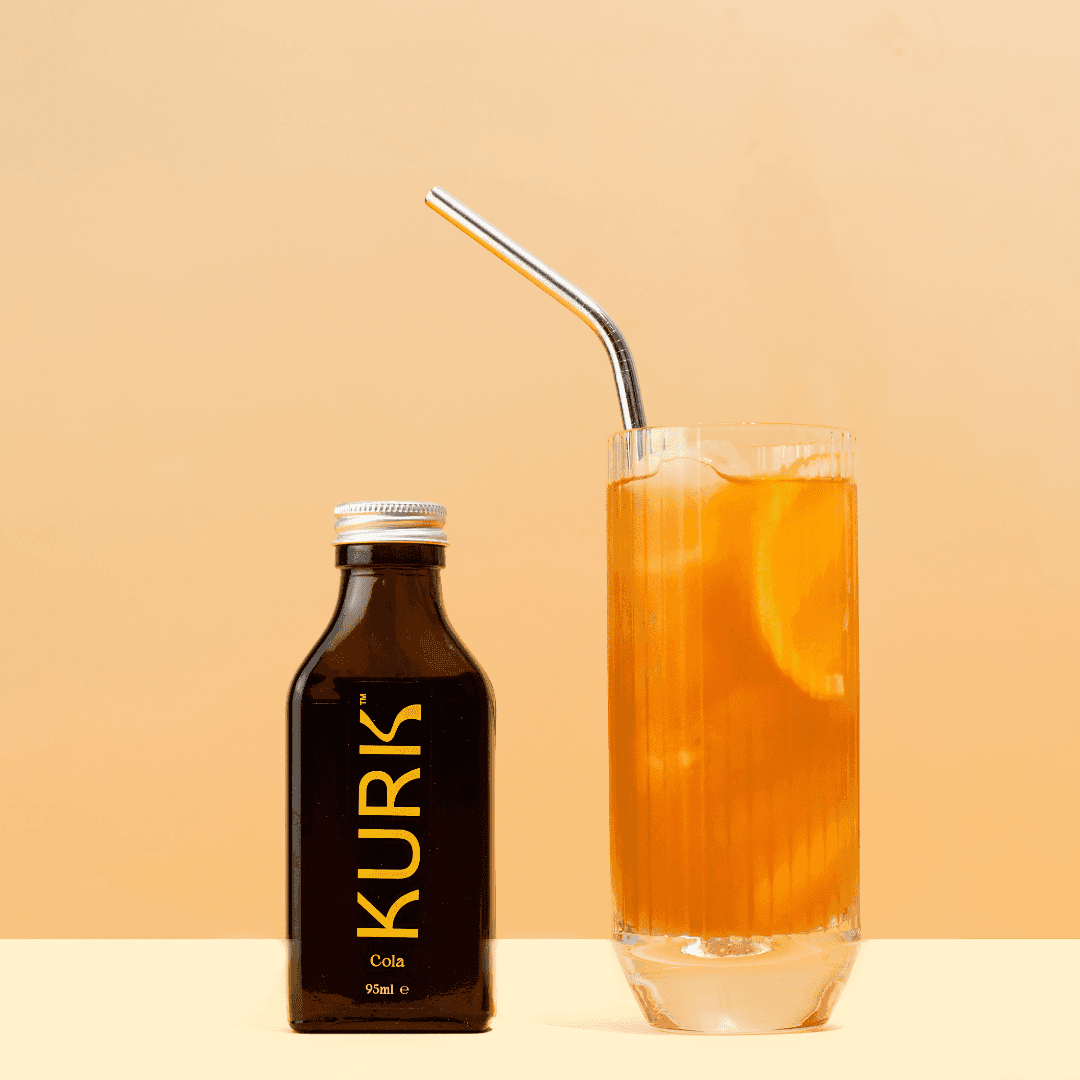 Kurk Cola Super Elixir - Health Booster | Curcumin Formula bottle beside a glass with curcumin infusion and turmeric powder, highlighting modern wellness.