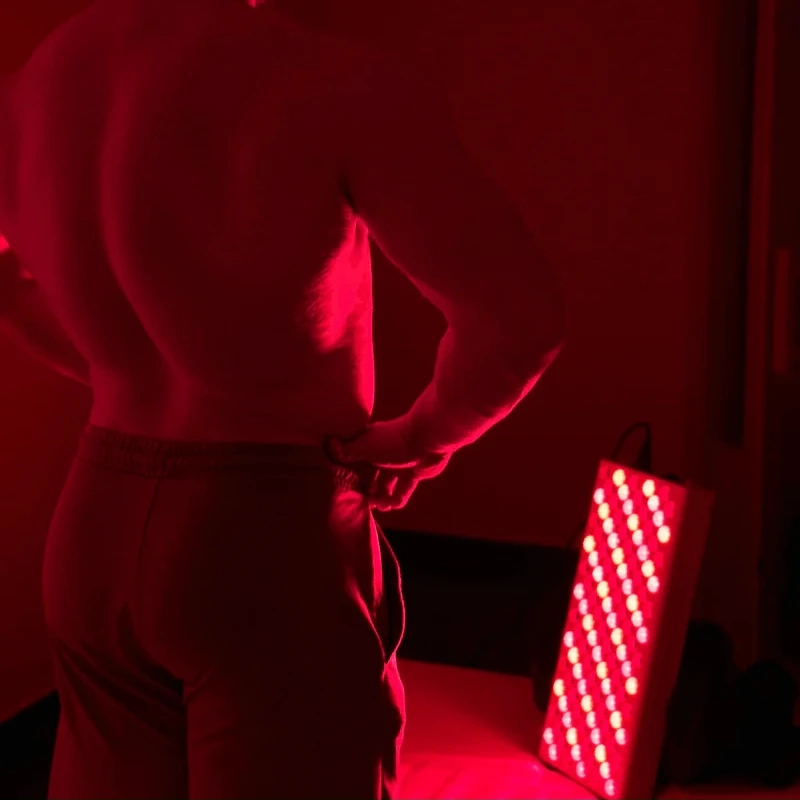 Back view of man using Red Light Elite Series 506 for lower back pain relief. Effective red light therapy for muscle recovery and inflammation.