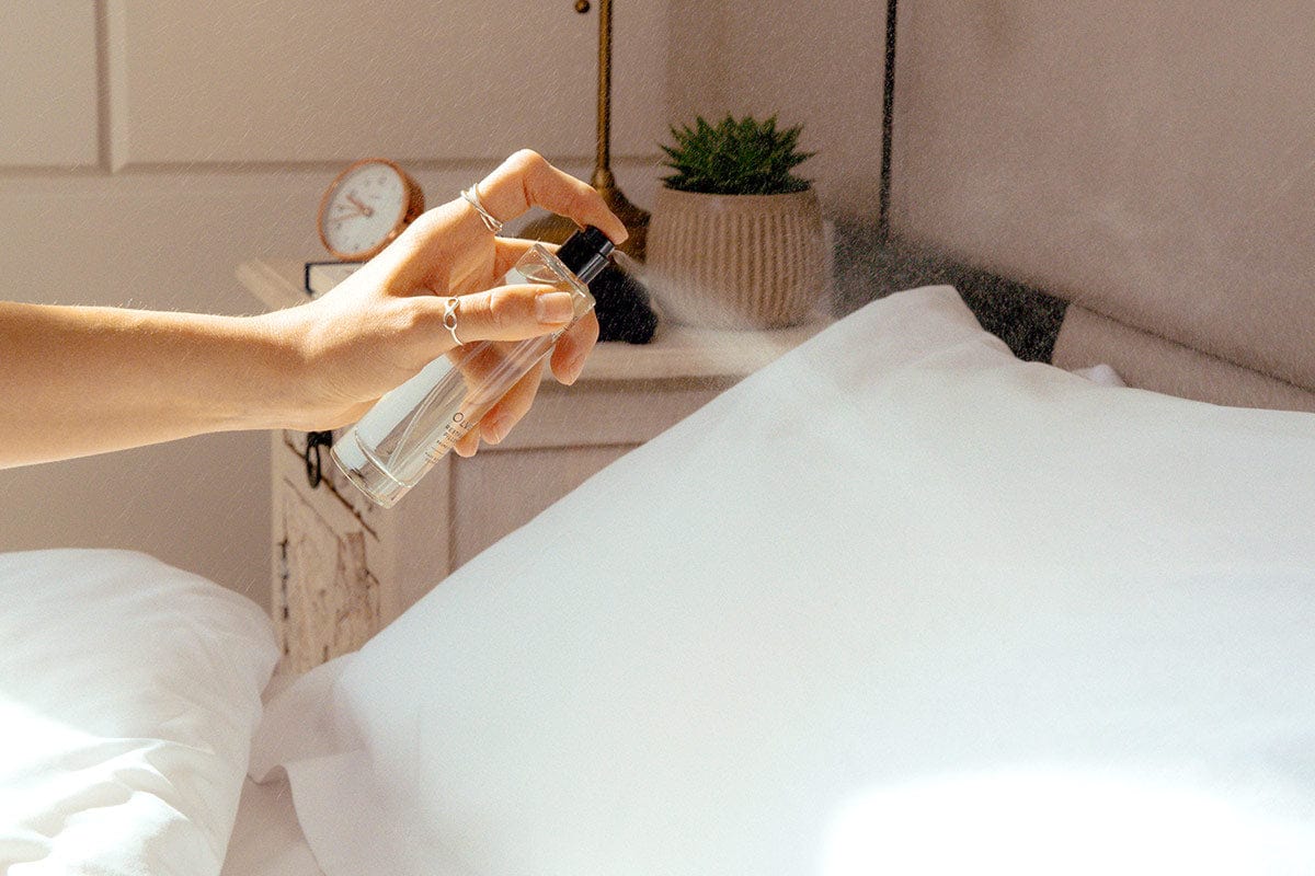 Spraying Olverum Restful Sleep Pillow Mist onto pillow, promoting restful sleep with essential oils in a serene bedroom setting.