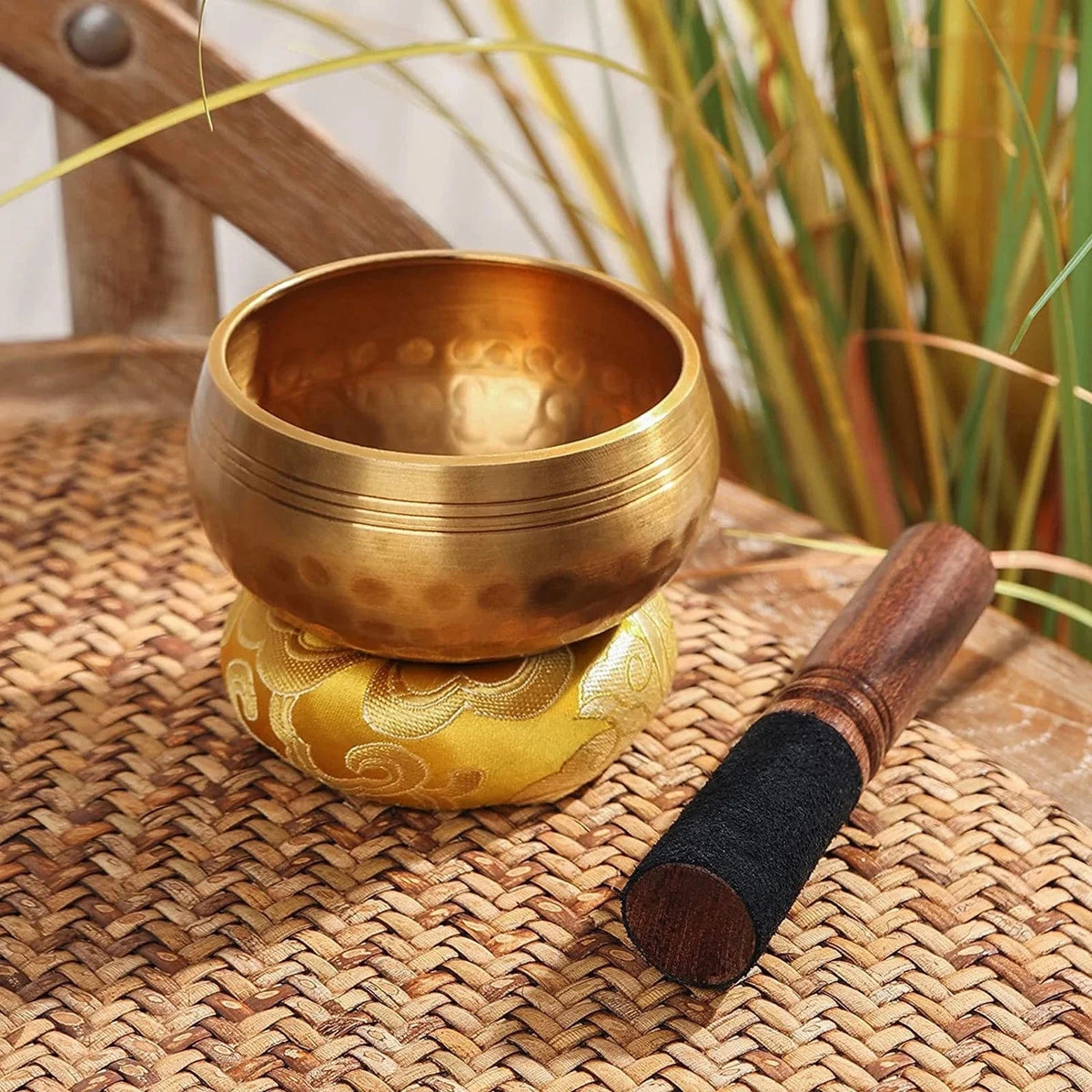 Handmade antique singing bowl with wooden mallet on red cushion, set in a forest stream for meditation and spiritual clarity.