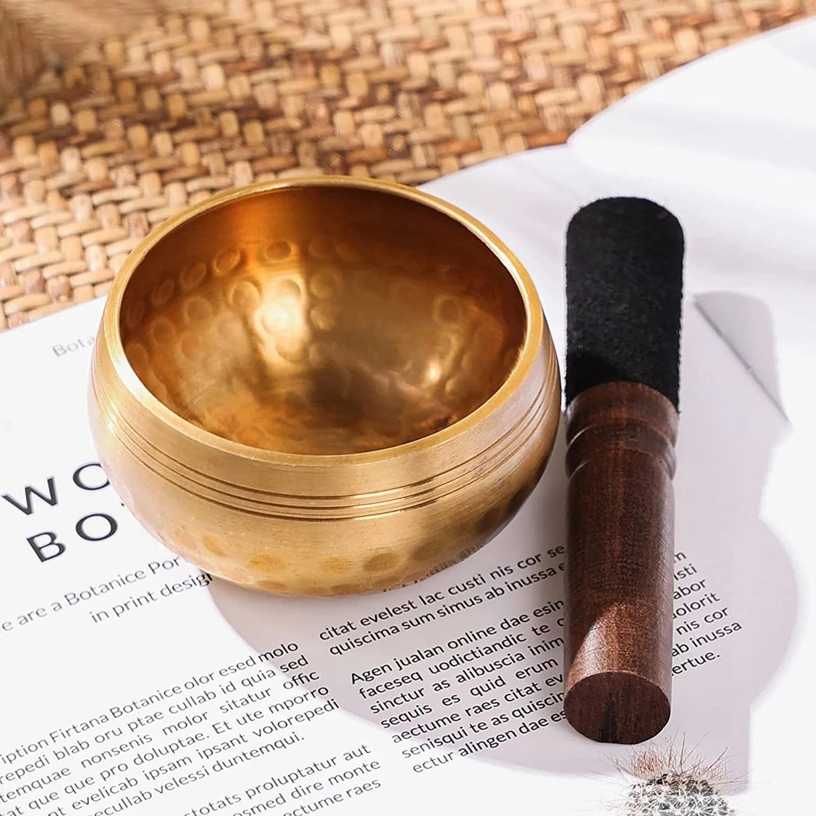 Handmade antique singing bowl with wooden mallet on red cushion, set in a forest stream for meditation and spiritual clarity.