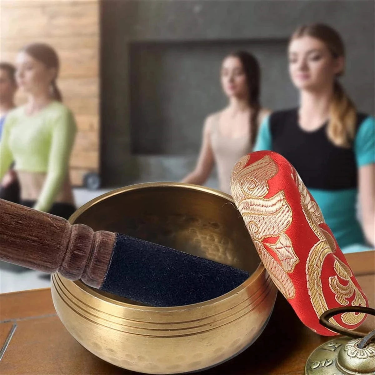 Handmade antique singing bowl with wooden mallet on red cushion, set in a forest stream for meditation and spiritual clarity.