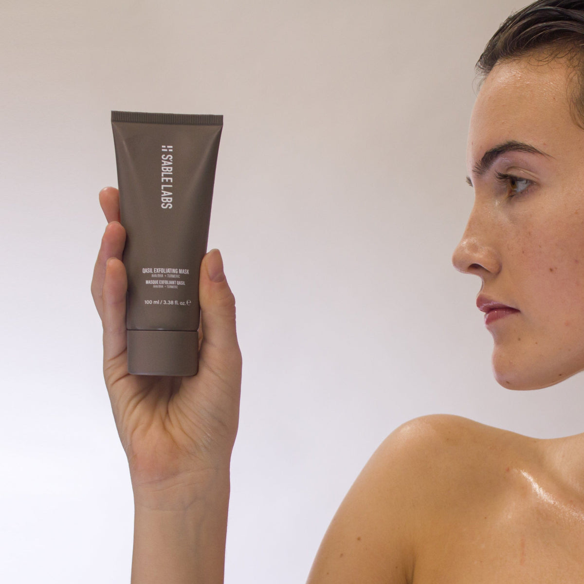 Qasil Exfoliating Mask - Brightening Face Exfoliant | AHAs, PHAs in sleek grey tube held by hand. Natural detoxifying skincare for glowing complexion.